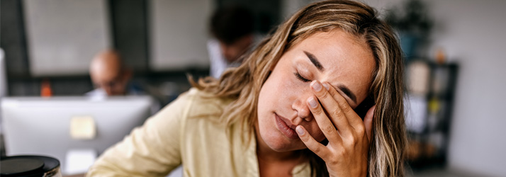 Chiropractic Porirua NZ Woman Sitting at Table With Head Pain Chiropractic Porirua NZ Woman Sitting at Table With Head Pain